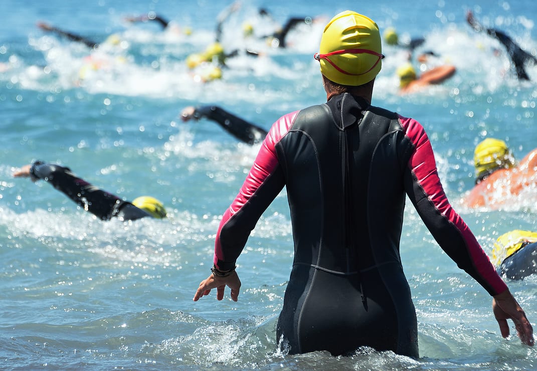 Group triathlon participants running into the water for swim portion of race