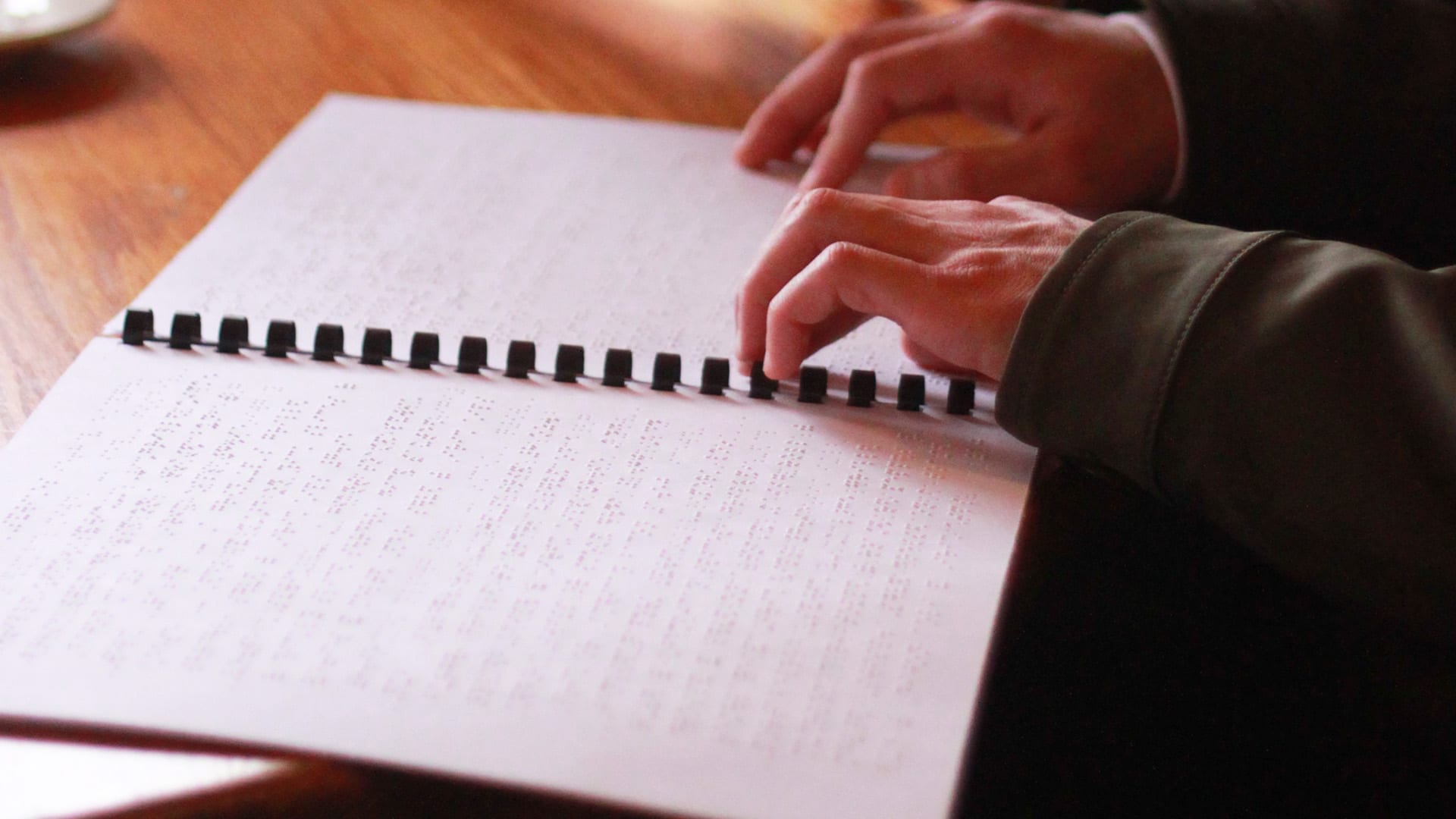 Someone reading braille at a meeting