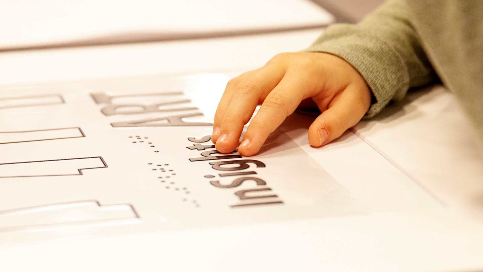 Child's hand on tactile graphic, graphic reads