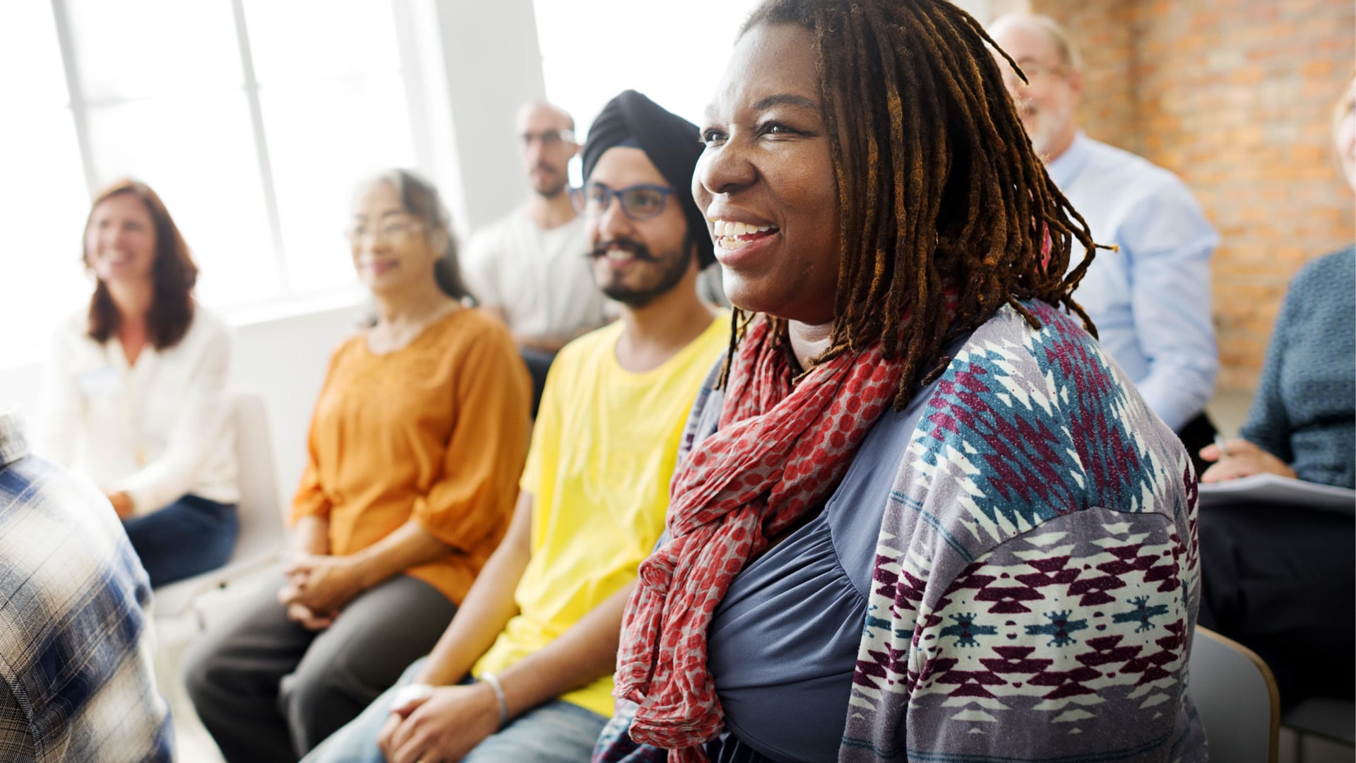 A diverse group of people looking to the front of the room and smiling