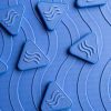 The textured side of the blue mat with blue triangle alphabet tiles scattered on top.