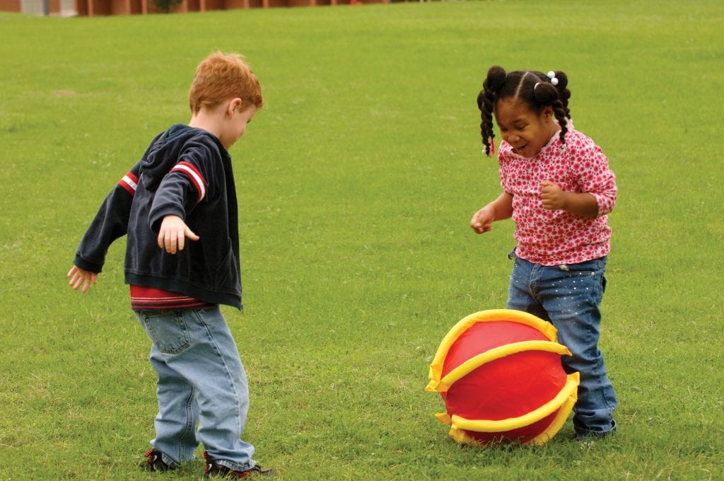 Young boy and girl playfully kicking a APH Rib-it Ball