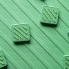 The textured side of the green mat with square green alphabet tiles scattered on top.