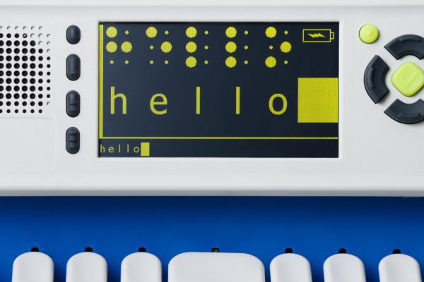 SMART Brailler with a black screen and lime green text that reads “Hello” in simbraille at top and large print then small print at bottom.