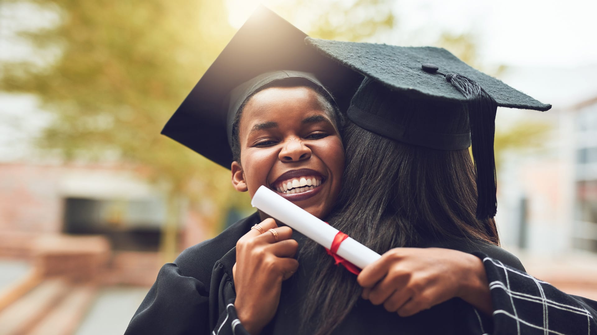 A young woman at her graduation hugging a friend