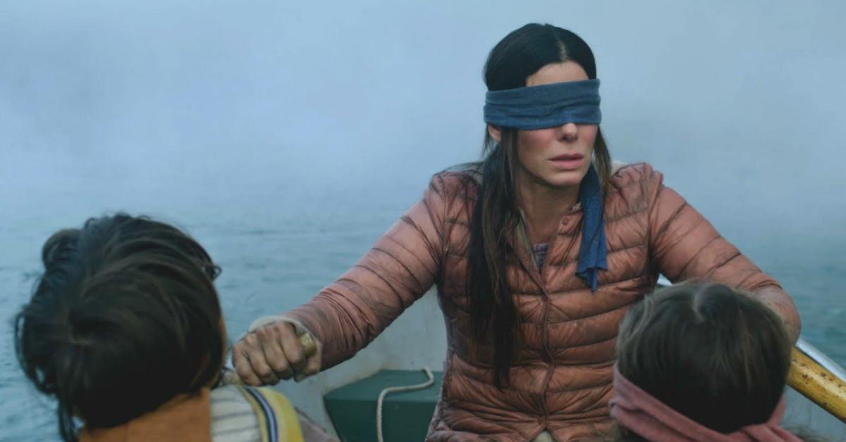 Sandra bullock in blindfold rowing a boat. Two children sit in front of her.