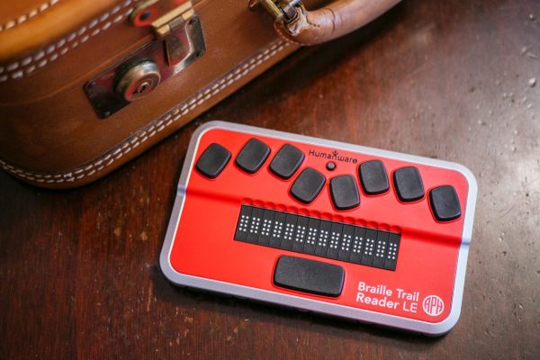 Braille Trail Reader next to a suitcase