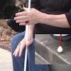 Close up of woman in wheelchair using cane to measure height of curb.