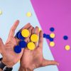 two hands holding blue and yellow tactile tokens