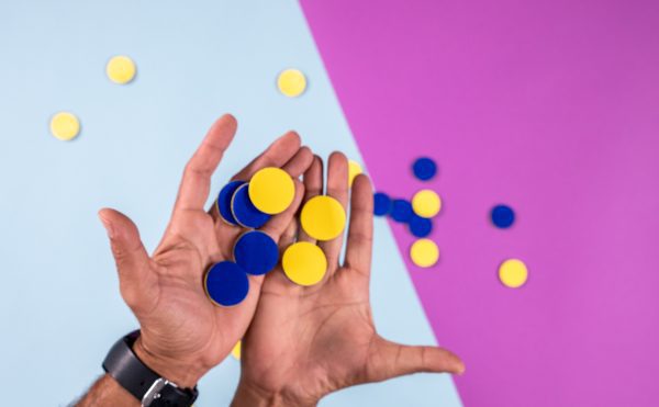 two hands holding blue and yellow tactile tokens