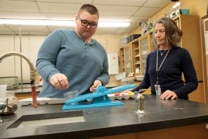 Student using the balance to measure the mass of an item with standard mass pieces.