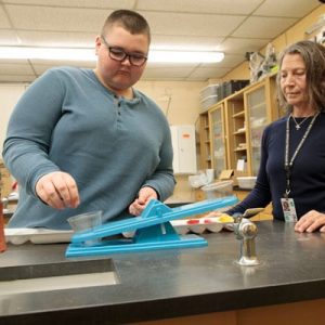 Student using the balance to measure the mass of an item with standard mass pieces.