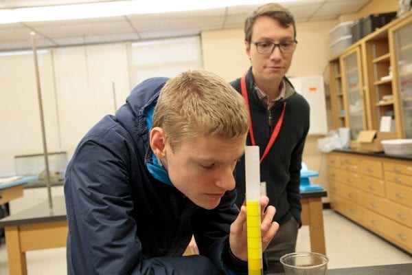 Student measuring the volume of liquid in a graduated cylinder.