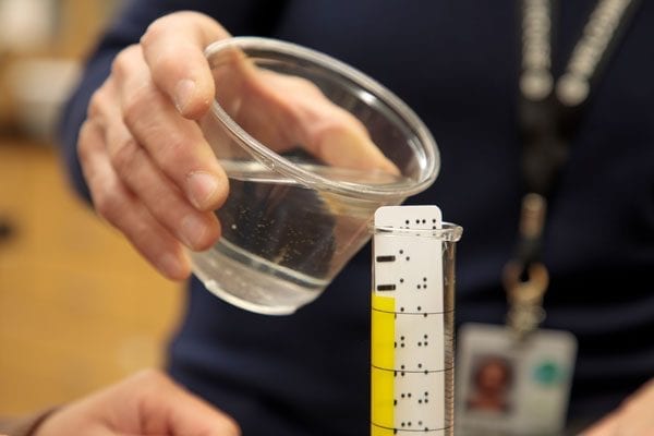 Student pouring water into an adapted graduated cylinder.