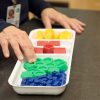 Sorting tray holding standard mass pieces of different colors and masses.