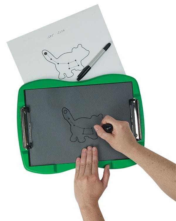 Two hands drawing a constellation with a bear outline on tactile drawing film attached to the green TactileDoodle frame. Above the frame is a printed sheet depicting the same image as the tactile drawing. A black marker rests on the page
