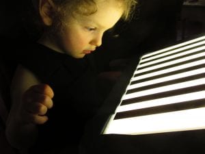 a child looking at a lightbox overlay in the dark