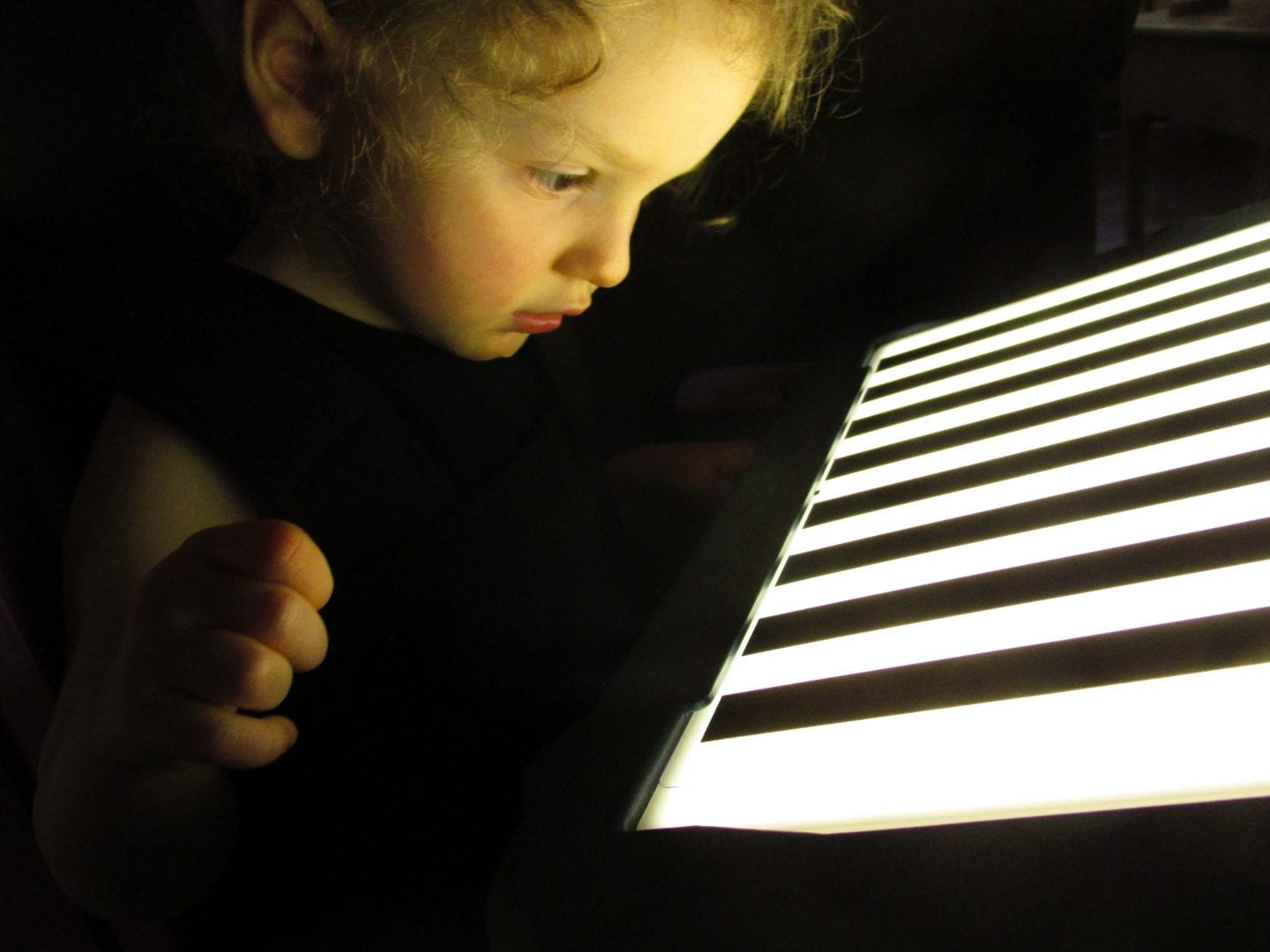 a child looking at a lightbox overlay in the dark