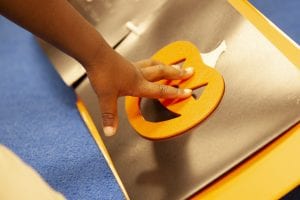 a child's hand feeling the foam pumkpin on the page