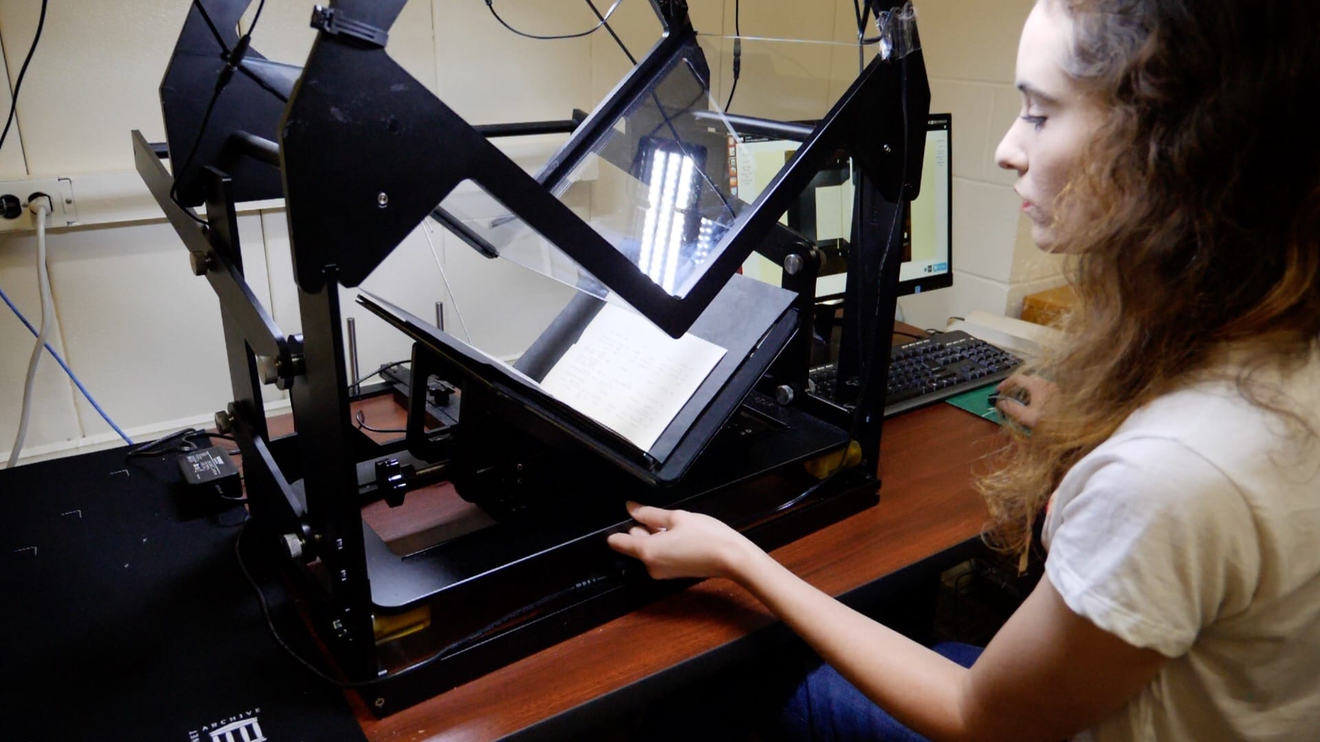 a woman using a machine to scan pages from an old book