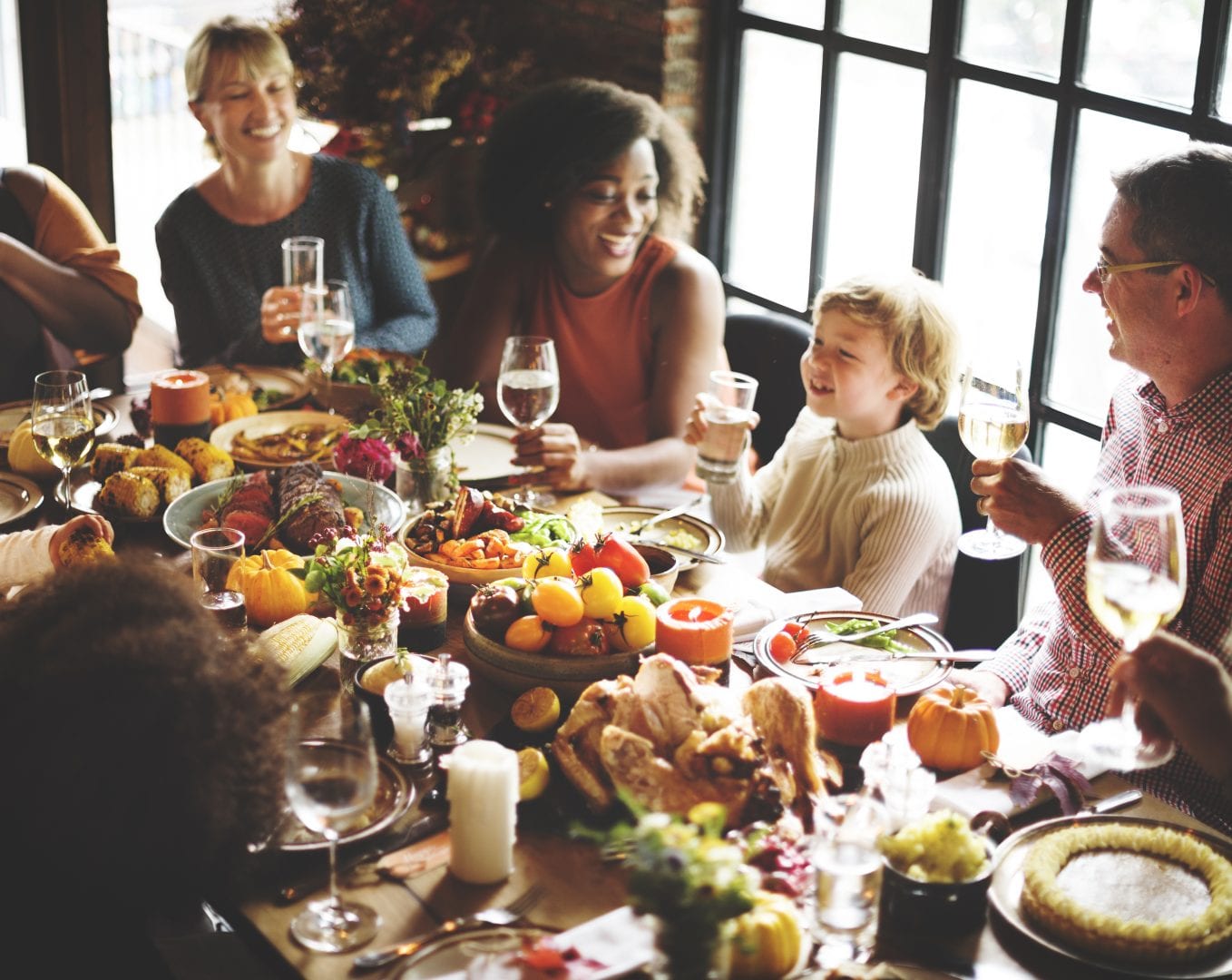 a group of adults and a child toasting at a thanksgiving meal