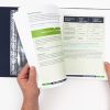 Two hands turning pages of an open blue Health Education guidebook binder.
