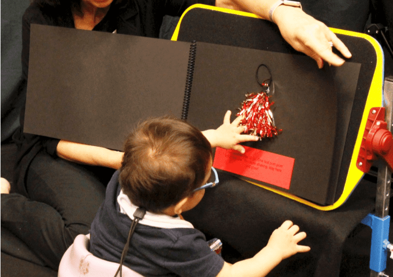 Diane and a child working with a yellow, black, and red CVI appropriate product