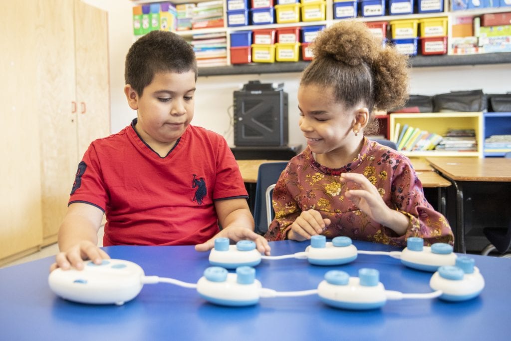 a boy and girl playing with code jumper in a classroom