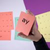 Close up of a red vowel blend sound card that reads "ay" in both print and braille. In the background are various sound card sheets.