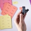 A hand holding a USB drive with black text that reads "Wilson Reading System UEB." In the background are perforated print-braille card sheets in various colors.