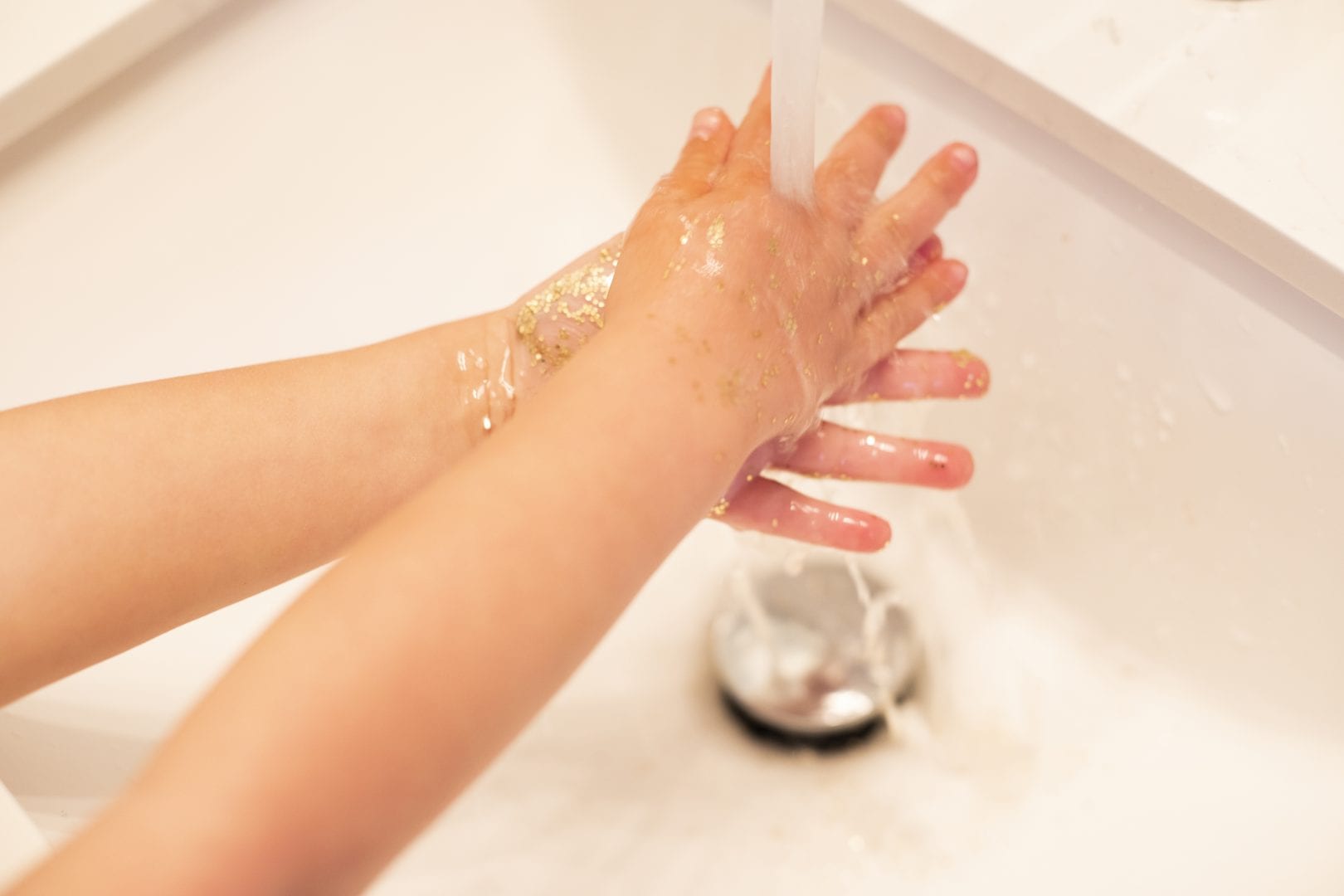 child washing their glitter covered hands