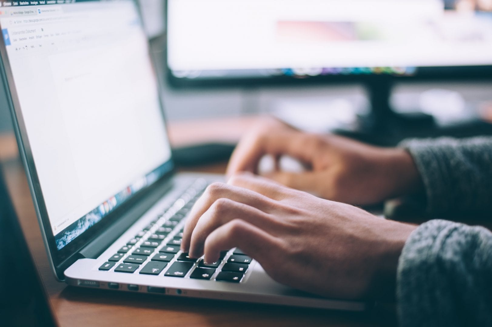 close up of hands on a keyboard, screen is out of focus