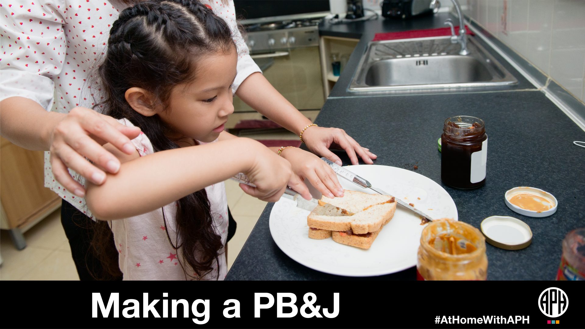 a child cutting a peanut butter sandwich with a parents help. text reads "Making a PB&J #AtHomeWithAPH"