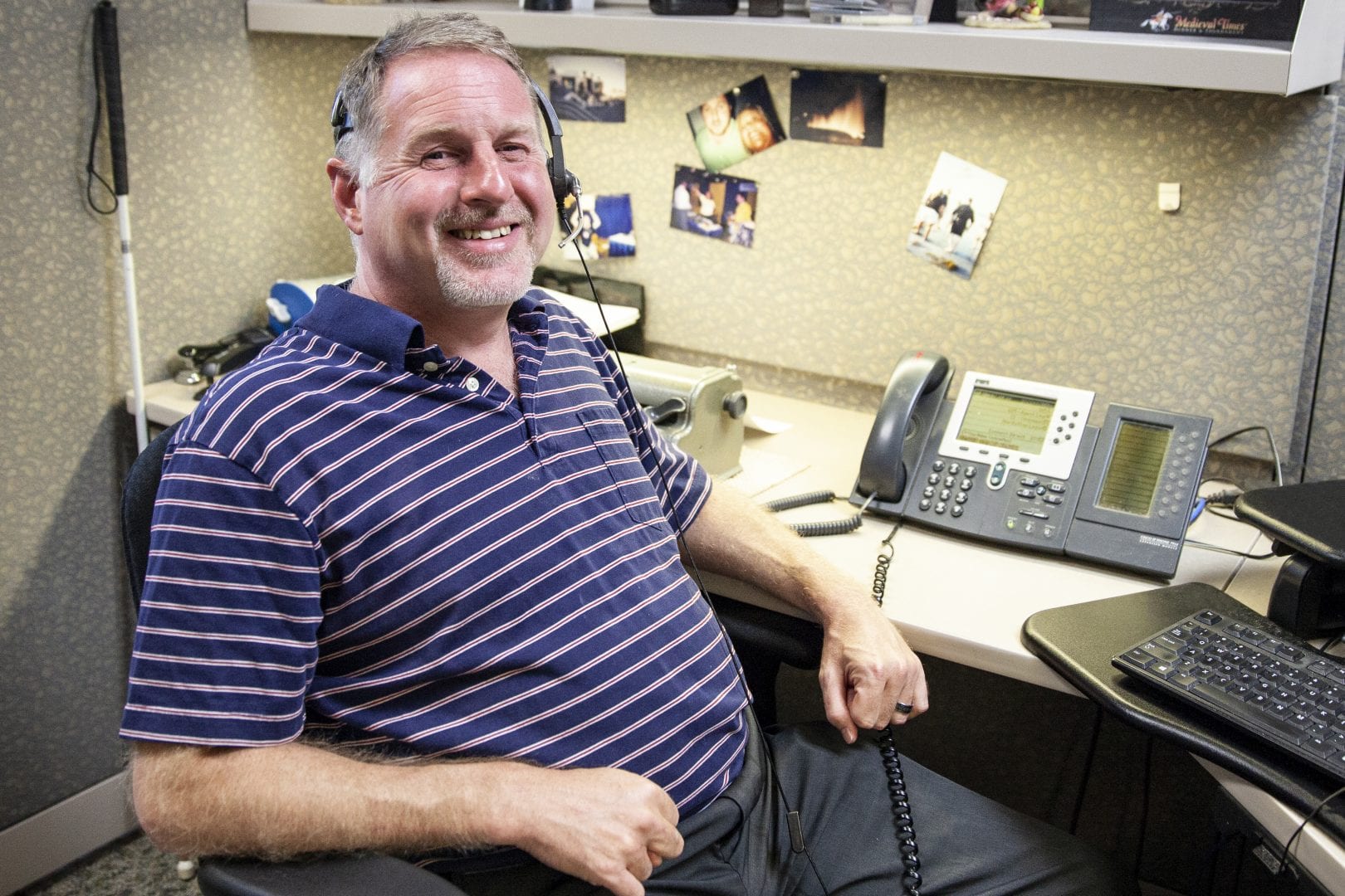 a man in a headset sitting at a desk smiling