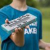 a student outside holding a chameleon 20 braille display in a teal case