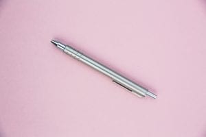 a silver pen on a light pink background