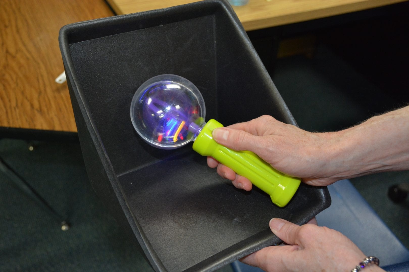 A teacher presents the object symbol for “Play Routine” in the learner’s now container of his object calendar.