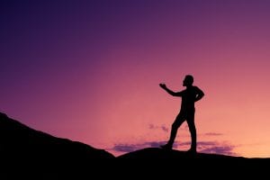 a person backlit by the sunrise doing tai chi