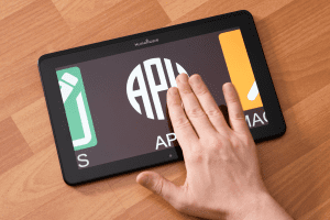 A hand reaches for the MATT Connect V2.1 tablet, which is displaying the APH logo.