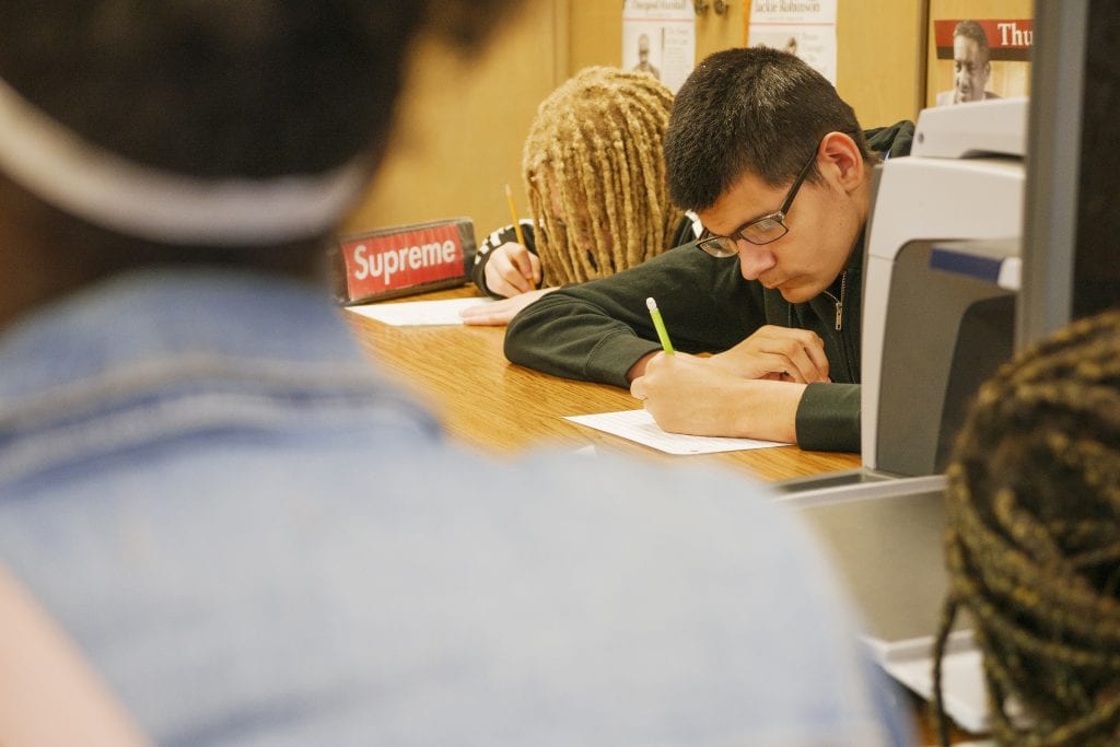 students with their heads bent working in a classroom