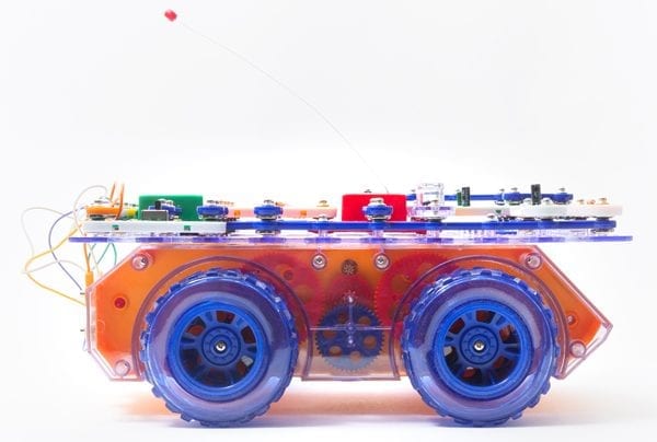 side view of RC Snap rover, a bread board covered in snap circuits pieces sitting on a frame with wheels.