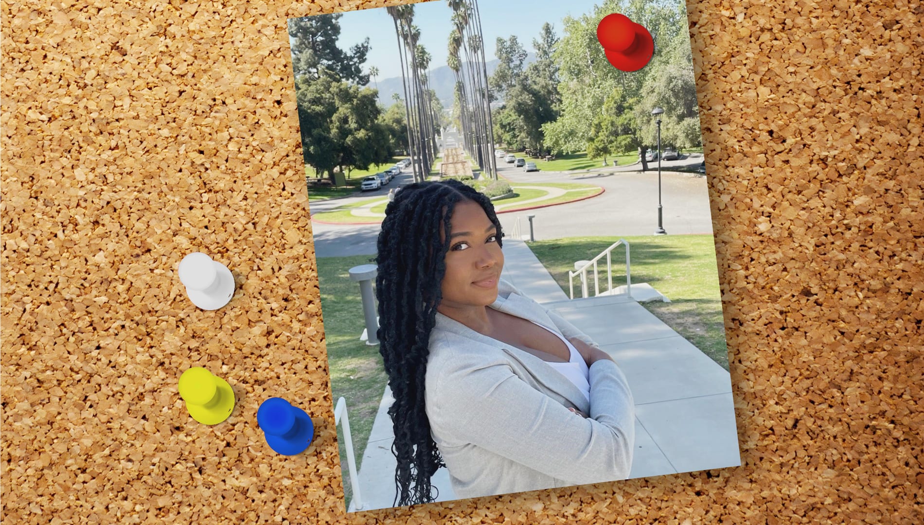 a photo of a woman smiling with her arms folded outdoors pinned to a cork board