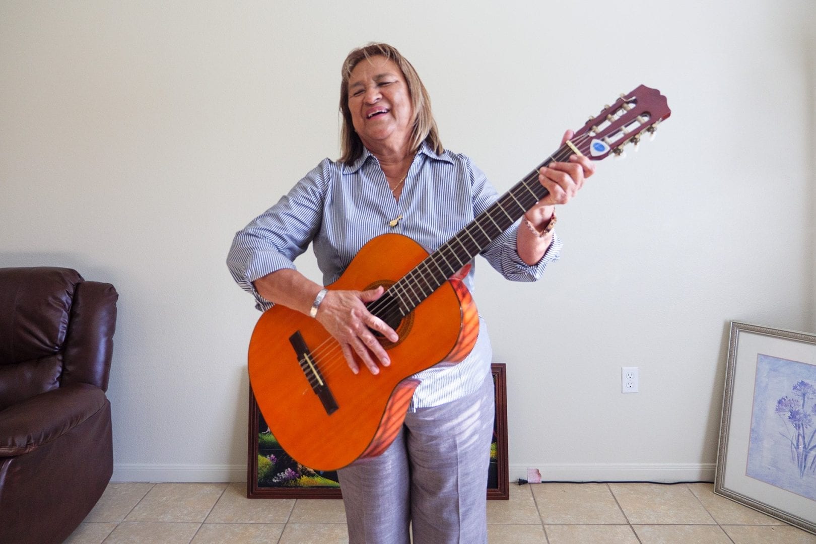 A smiling woman playing an acoustic guitar