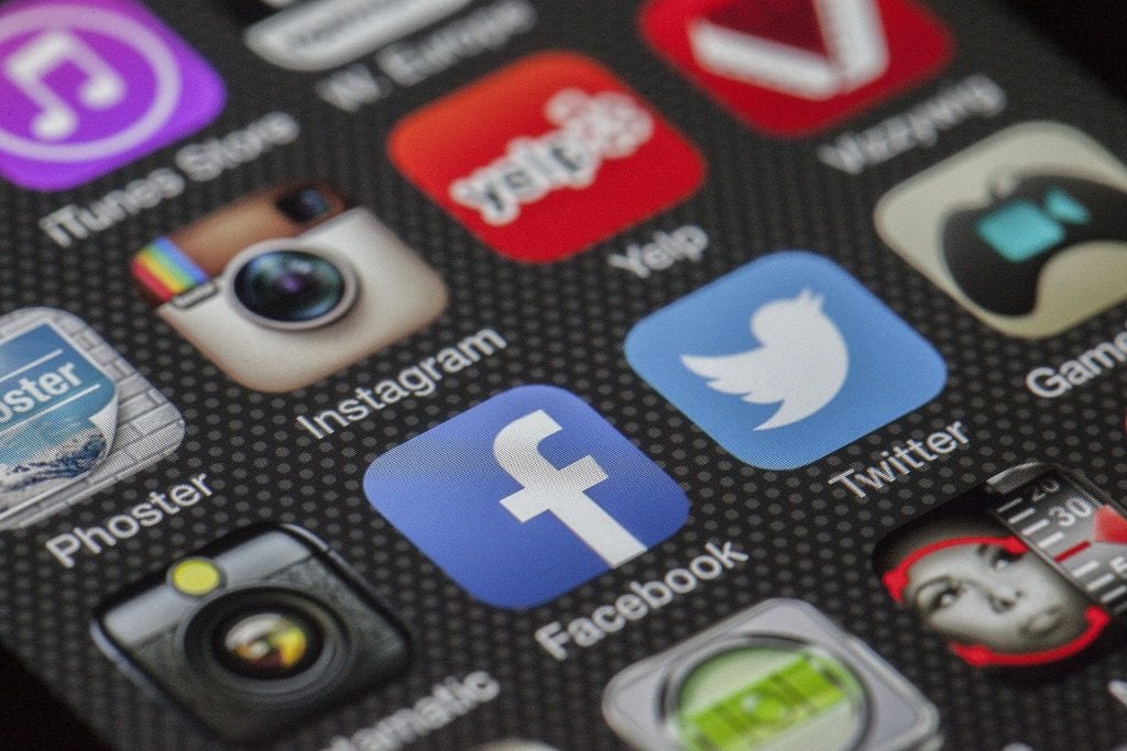 close up of a phone screen displaying a variety of apps including, Facebook, Twitter, and Instagram