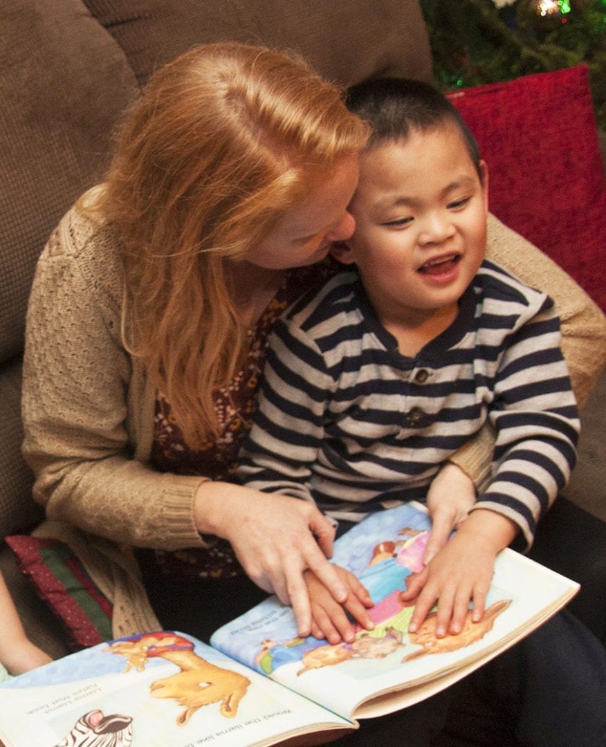 A mother reading a Braille Tales print/braille book with her child