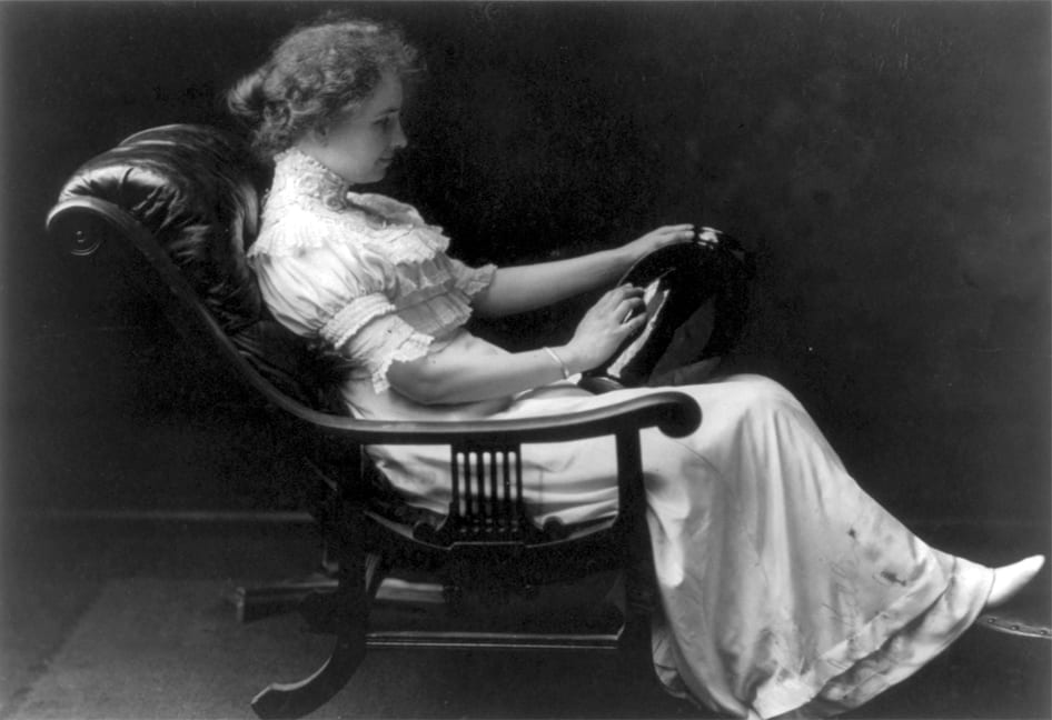Helen sitting back in a chair with a reclined back. The arms are wood and the seat and backrest are plushly stuffed leather