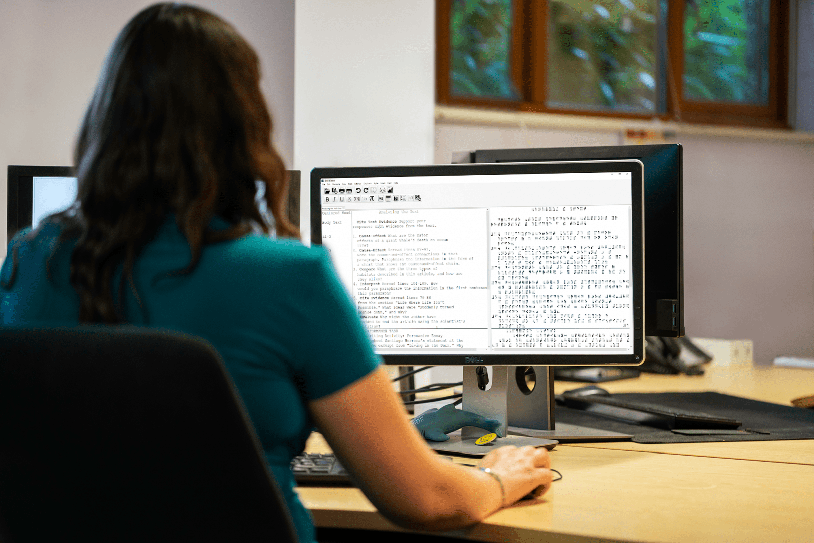 image of a woman sitting at a desk using brailleblaster on a computer