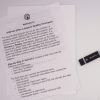 A copy of the Step-by-Step user guide printed on white paper laid on a white surface next to the black Step-by-Step Part 1 USB thumb drive.