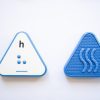The front and back of a blue, triangular Reach & Match Alphabet Tile showing the letter h in print and braille.