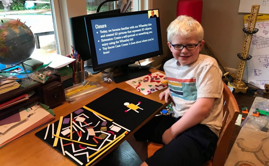 a student smiling in front of a computer with a presentation on the screen. the Picture Maker Wheatley Tactile Diagramming Kit sits on the table next to them showing extra pieces to the left and the figure of a person on the right.